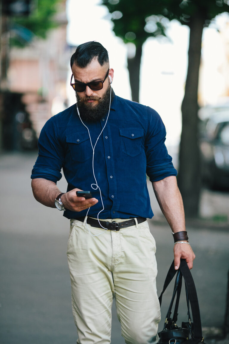 bearded man walks down the street and listening to music